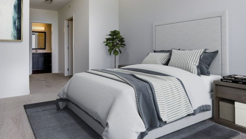 Spacious primary bedroom with soft gray palette, upholstered bed, and ensuite bath entry at 1225 Old Town Apartments in Chicago, designed for quiet comfort