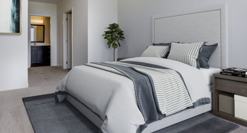 Spacious primary bedroom with soft gray palette, upholstered bed, and ensuite bath entry at 1225 Old Town Apartments in Chicago, designed for quiet comfort