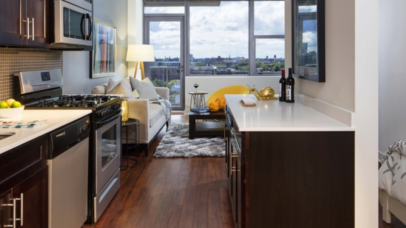 Studio layout featuring a galley kitchen with stainless appliances and a cozy living area near large windows at 1225 Old Town Apartments, Chicago