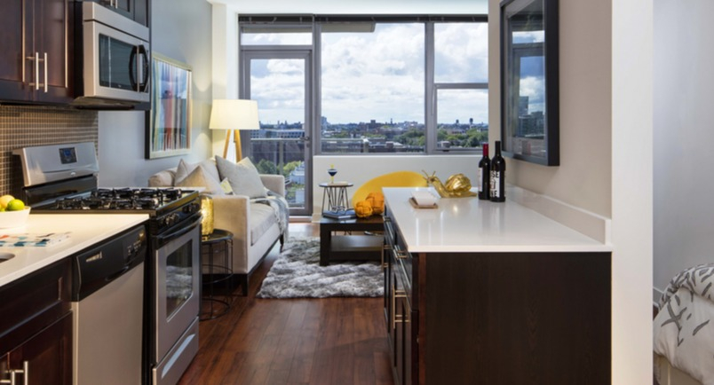 Studio layout featuring a galley kitchen with stainless appliances and a cozy living area near large windows at 1225 Old Town Apartments, Chicago