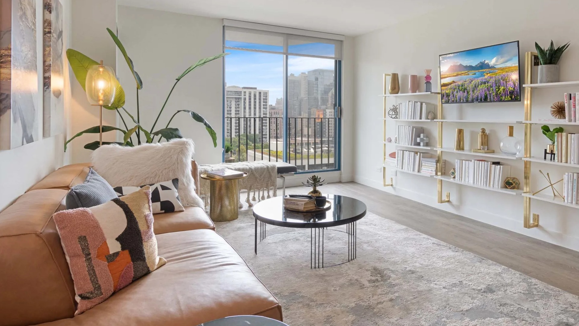 Cozy living area with tan sectional, built-in shelving, and balcony doors showcasing Chicago skyline views at 1250 LaSalle apartments