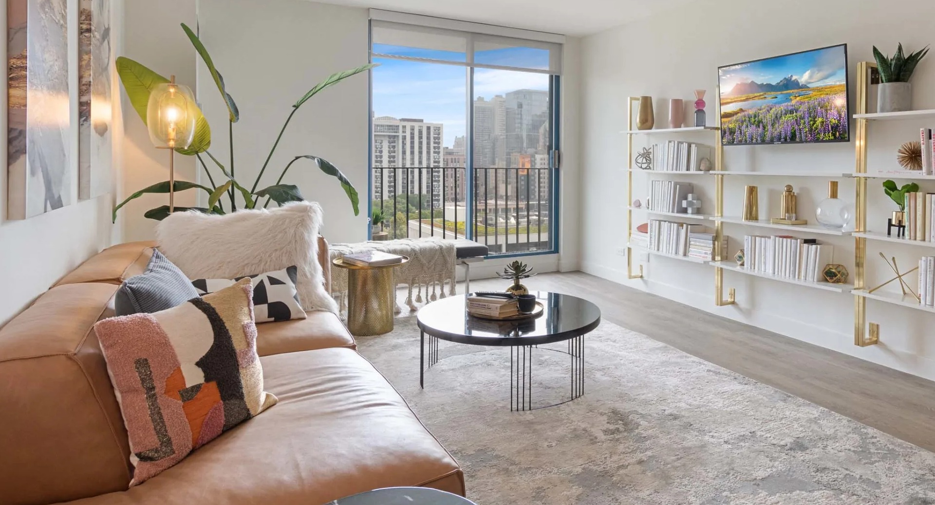 Cozy living area with tan sectional, built-in shelving, and balcony doors showcasing Chicago skyline views at 1250 LaSalle apartments