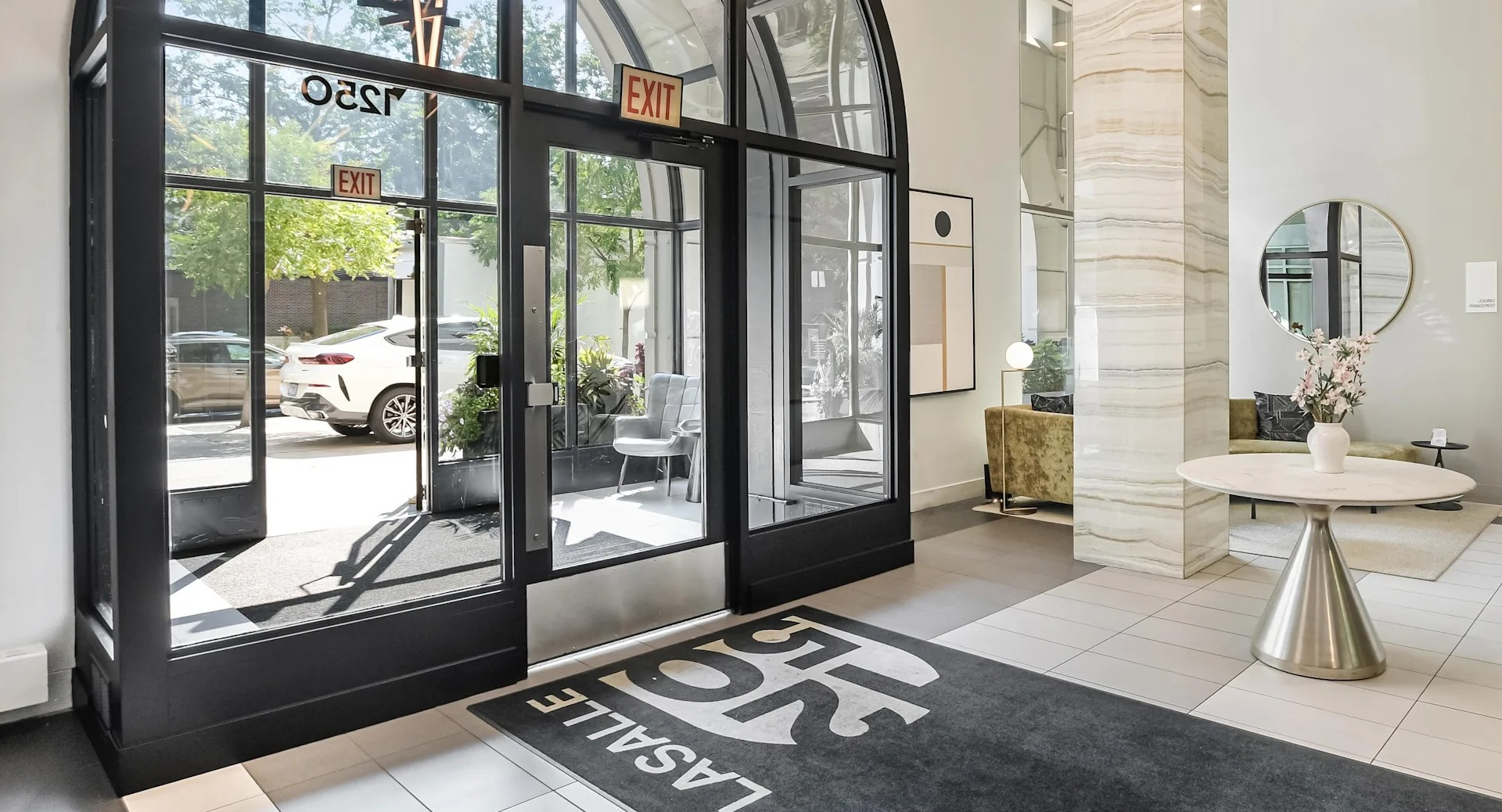 Elegant lobby entrance at 1250 LaSalle featuring dramatic arched glass doors, sculptural lighting, and welcoming seating by bright windows