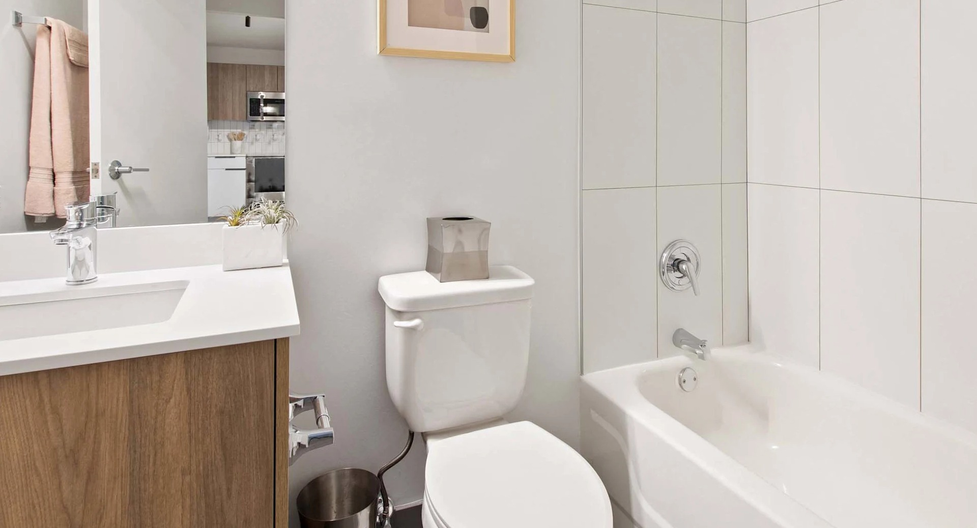 Modern bathroom at 1250 LaSalle with white tiled shower-tub combo, sleek vanity with wood accents, and bright contemporary lighting