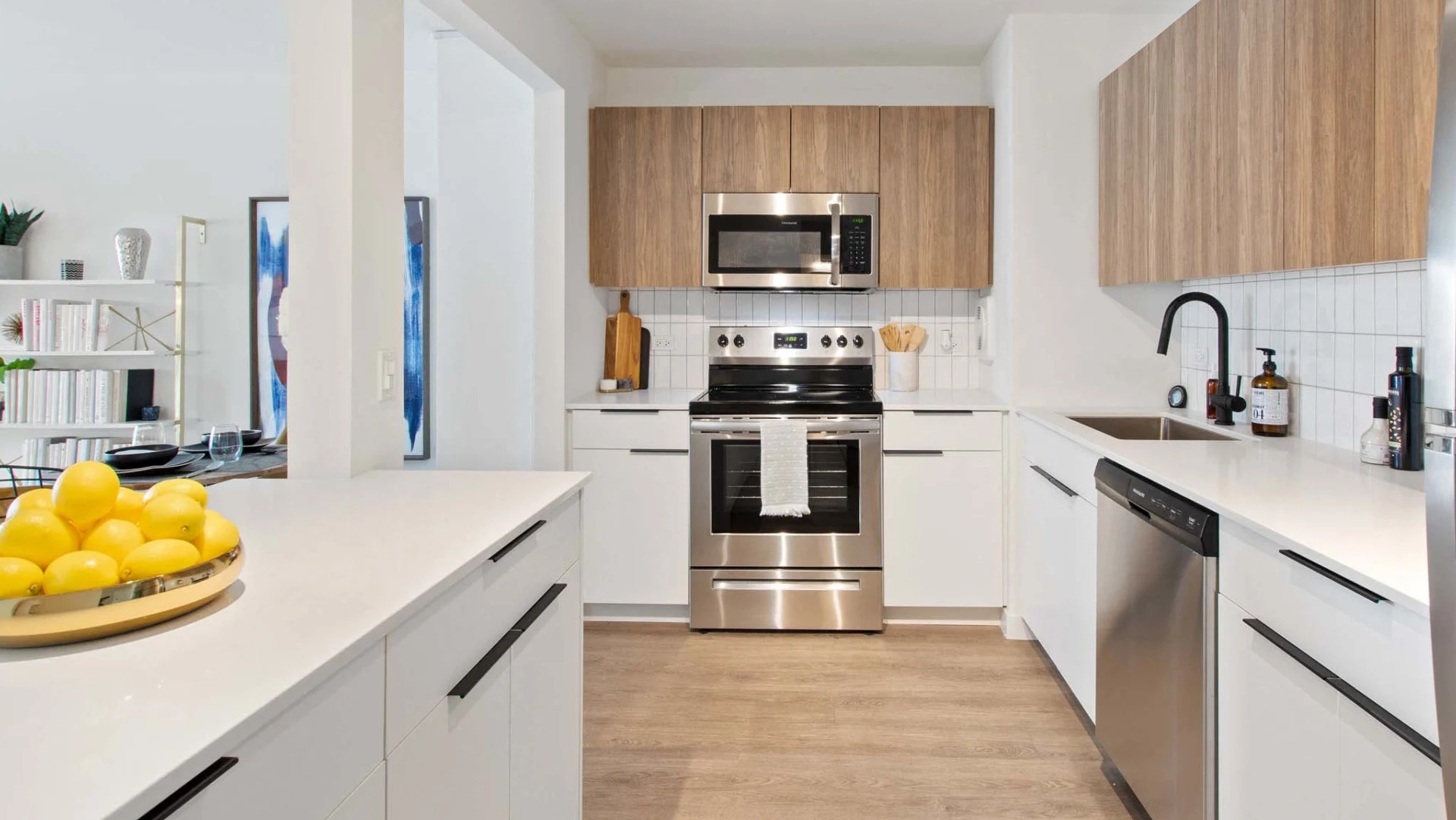 Modern kitchen at 1250 LaSalle with stainless steel appliances, white quartz counters, warm wood upper cabinets, and a tile backsplash