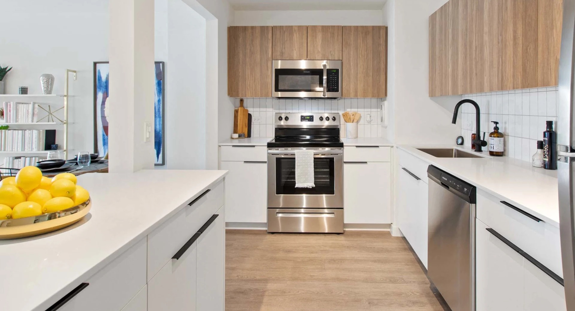 Modern kitchen at 1250 LaSalle with stainless steel appliances, white quartz counters, warm wood upper cabinets, and a tile backsplash