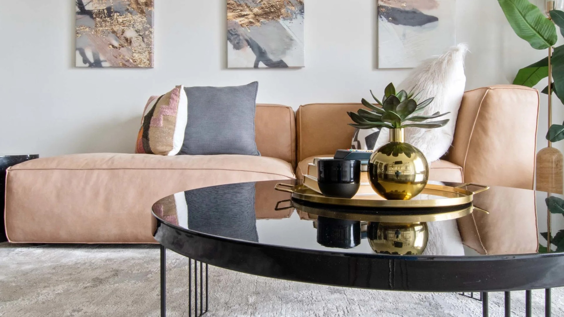 Modern living room at 1250 LaSalle with abstract triptych art, plush pillows, and a glossy round coffee table over a soft area rug