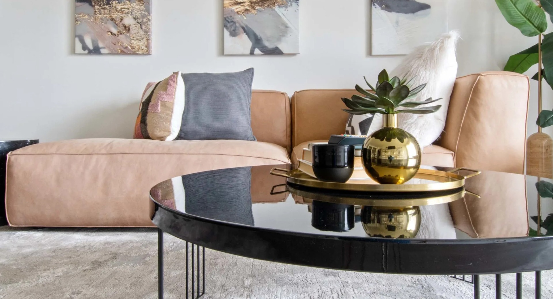 Modern living room at 1250 LaSalle with abstract triptych art, plush pillows, and a glossy round coffee table over a soft area rug