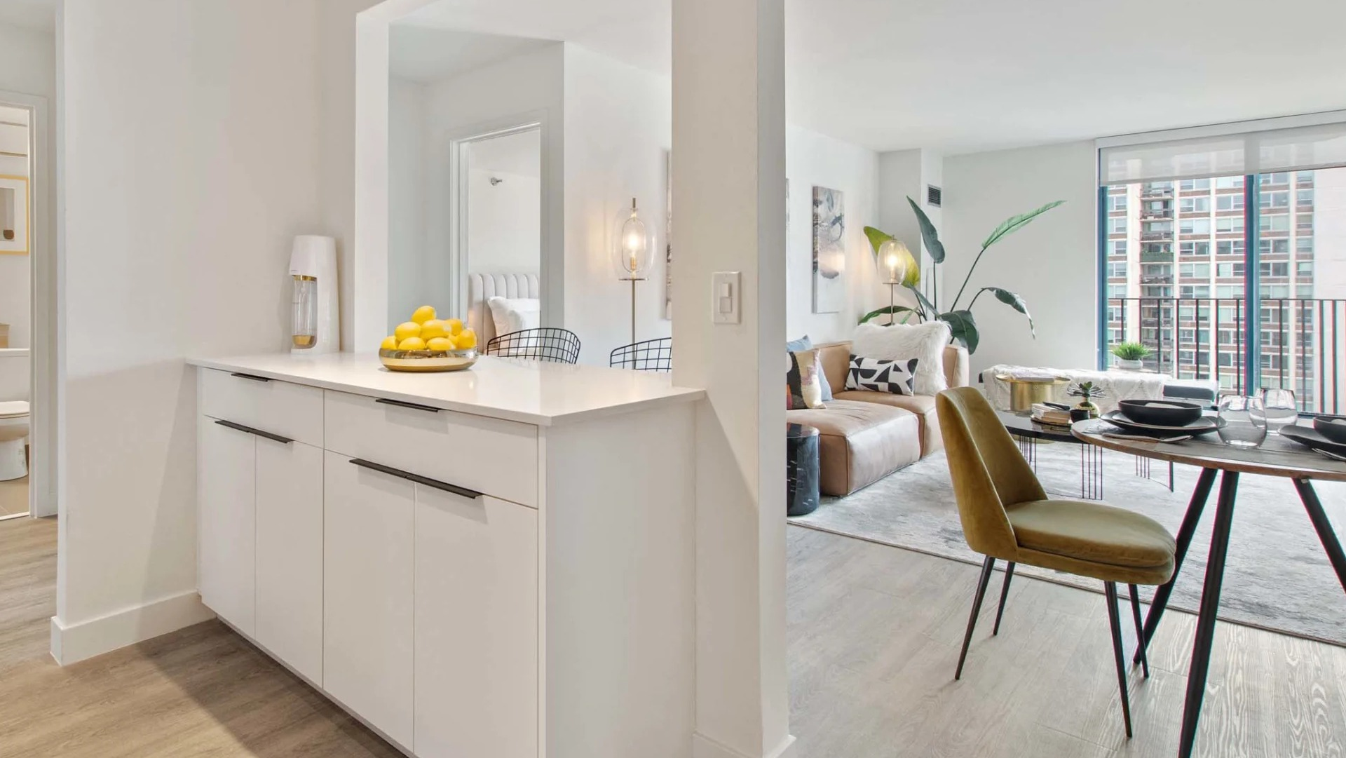 Open-concept dining and living space at 1250 LaSalle featuring a pass-through counter, track lighting, and large windows for natural light