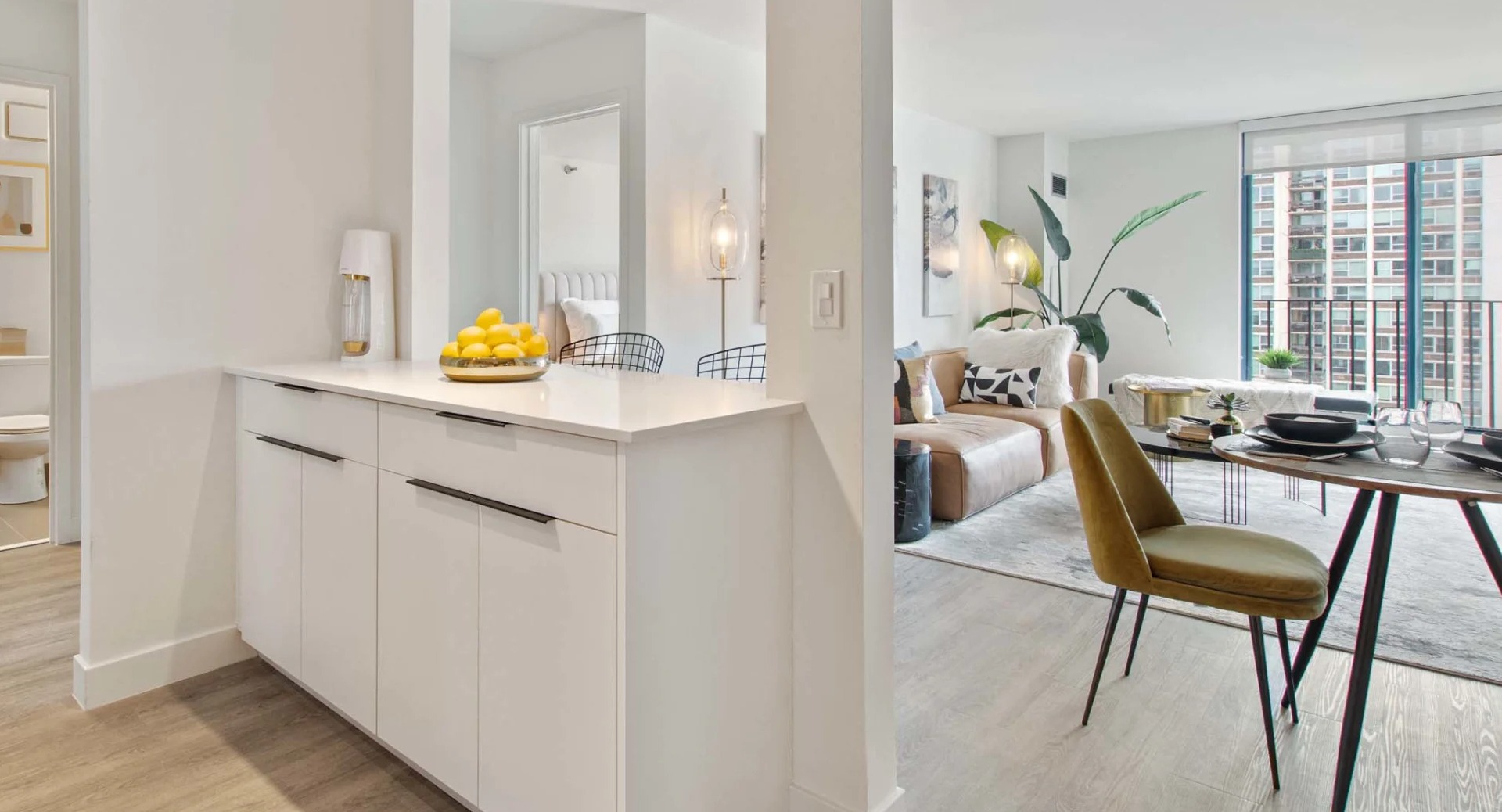 Open-concept dining and living space at 1250 LaSalle featuring a pass-through counter, track lighting, and large windows for natural light