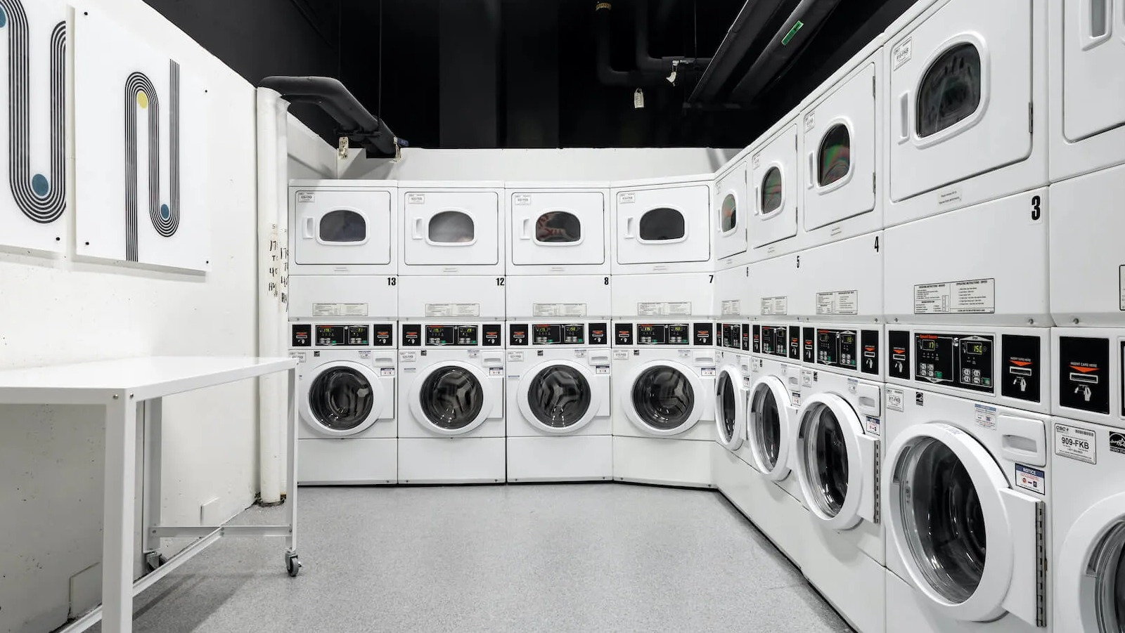 Resident laundry room at 1250 LaSalle in Chicago offering rows of front-loading washers and stacked dryers, folding space, and bright modern lighting