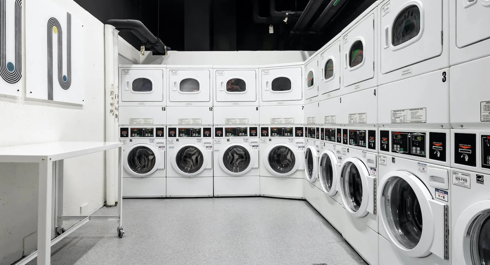 Resident laundry room at 1250 LaSalle in Chicago offering rows of front-loading washers and stacked dryers, folding space, and bright modern lighting