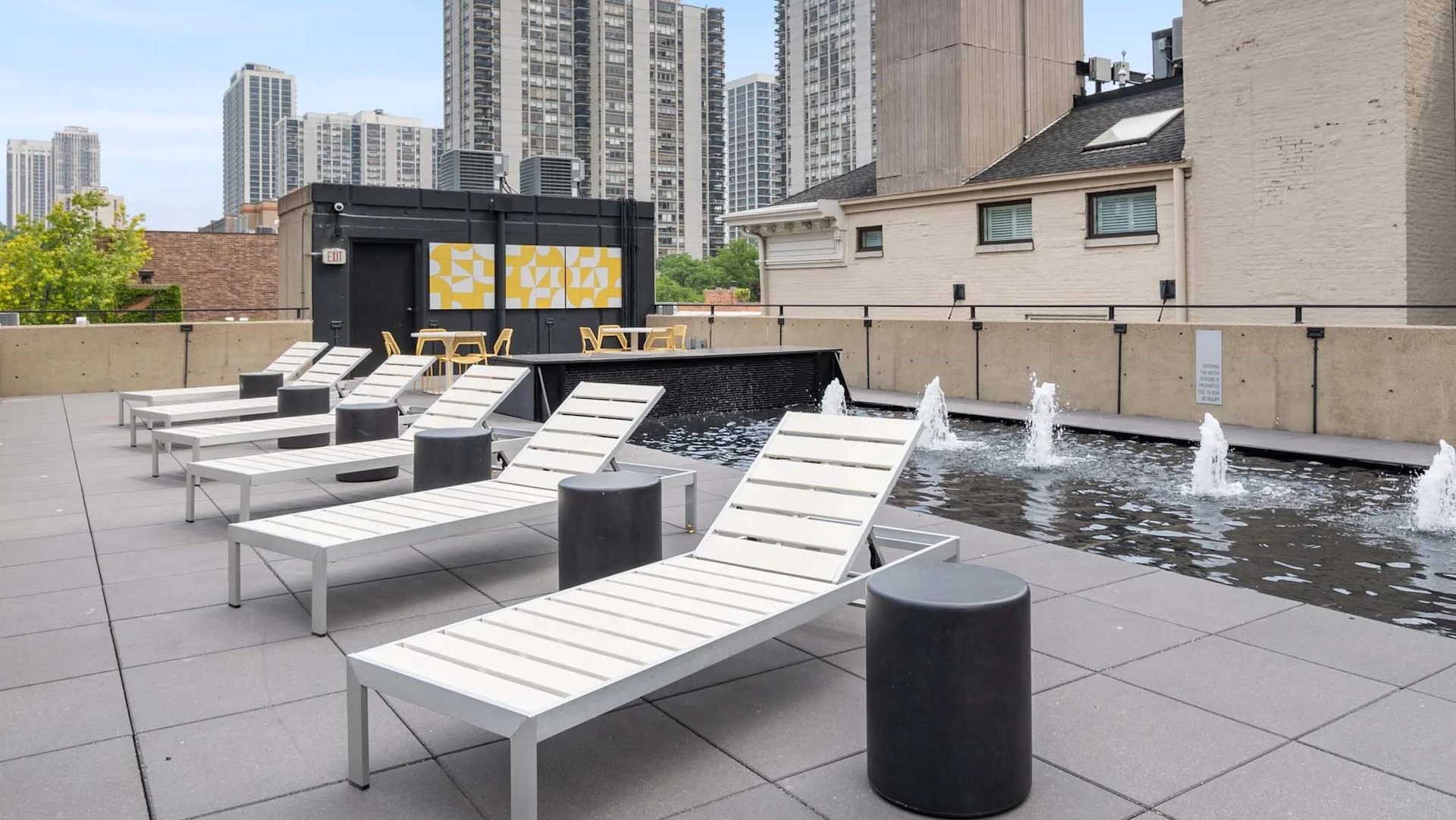 Rooftop sundeck at 1250 LaSalle in Chicago with chaise loungers beside a long fountain with water spouts, open space, and city views for relaxing