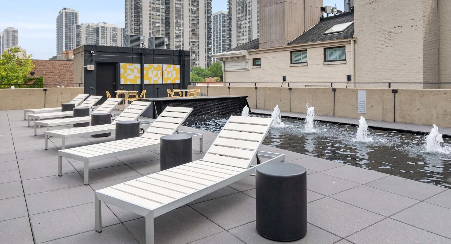 Rooftop sundeck at 1250 LaSalle in Chicago with chaise loungers beside a long fountain with water spouts, open space, and city views for relaxing