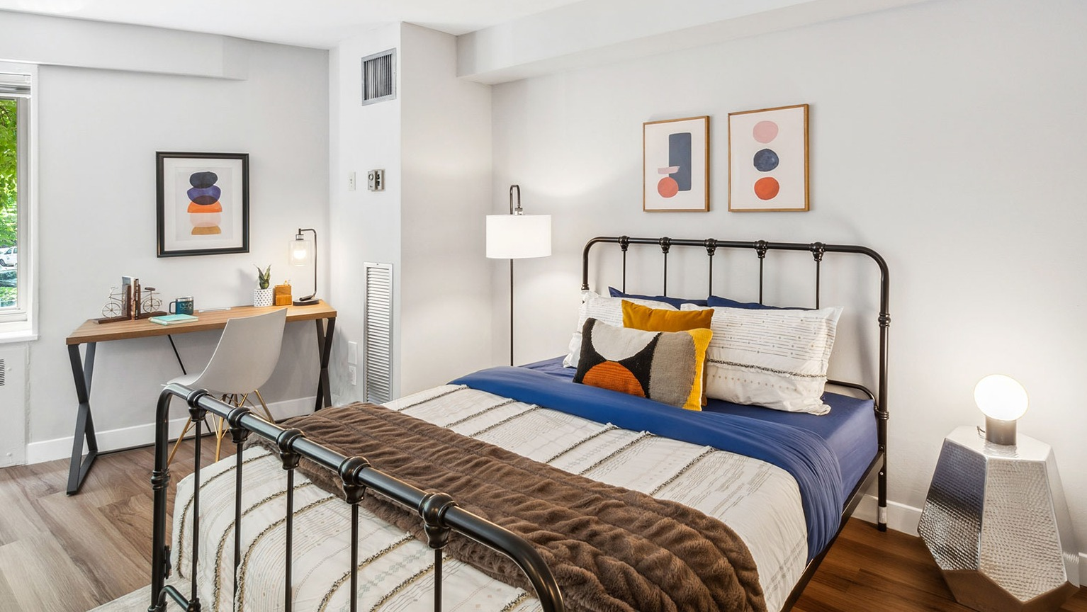 Cozy studio sleeping area with metal bed frame, layered bedding, and bedside lighting at 1350–1360 Lake Shore Drive apartments in Chicago