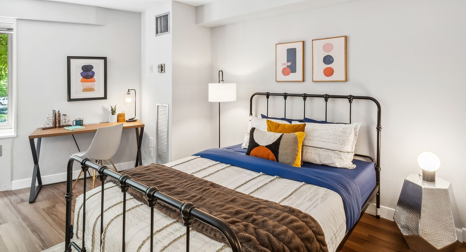 Cozy studio sleeping area with metal bed frame, layered bedding, and bedside lighting at 1350–1360 Lake Shore Drive apartments in Chicago