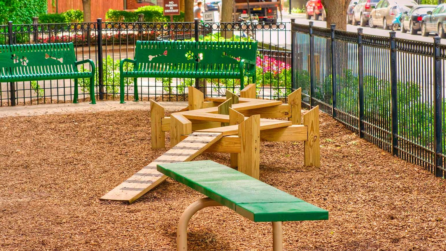 Fenced dog park featuring agility ramps, benches, and mulch surfacing at 1350-1360 Lake Shore Drive apartments in Chicago