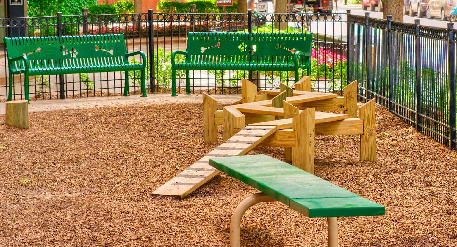 Fenced dog park featuring agility ramps, benches, and mulch surfacing at 1350-1360 Lake Shore Drive apartments in Chicago