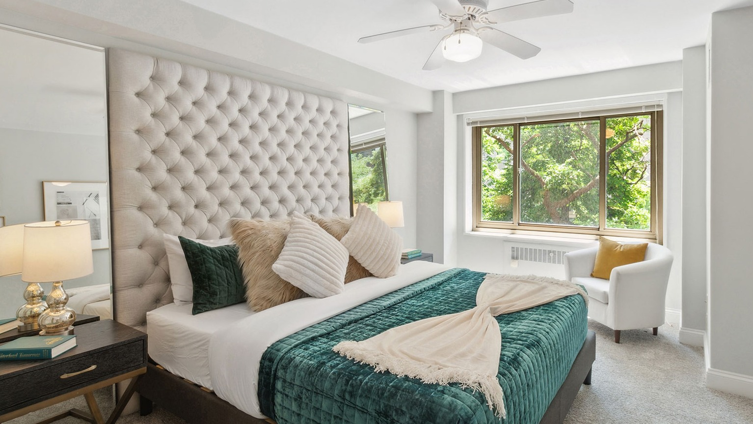 Serene bedroom with tufted headboard, ceiling fan, large window, and plush bedding at 1350–1360 Lake Shore Drive apartments in Chicago