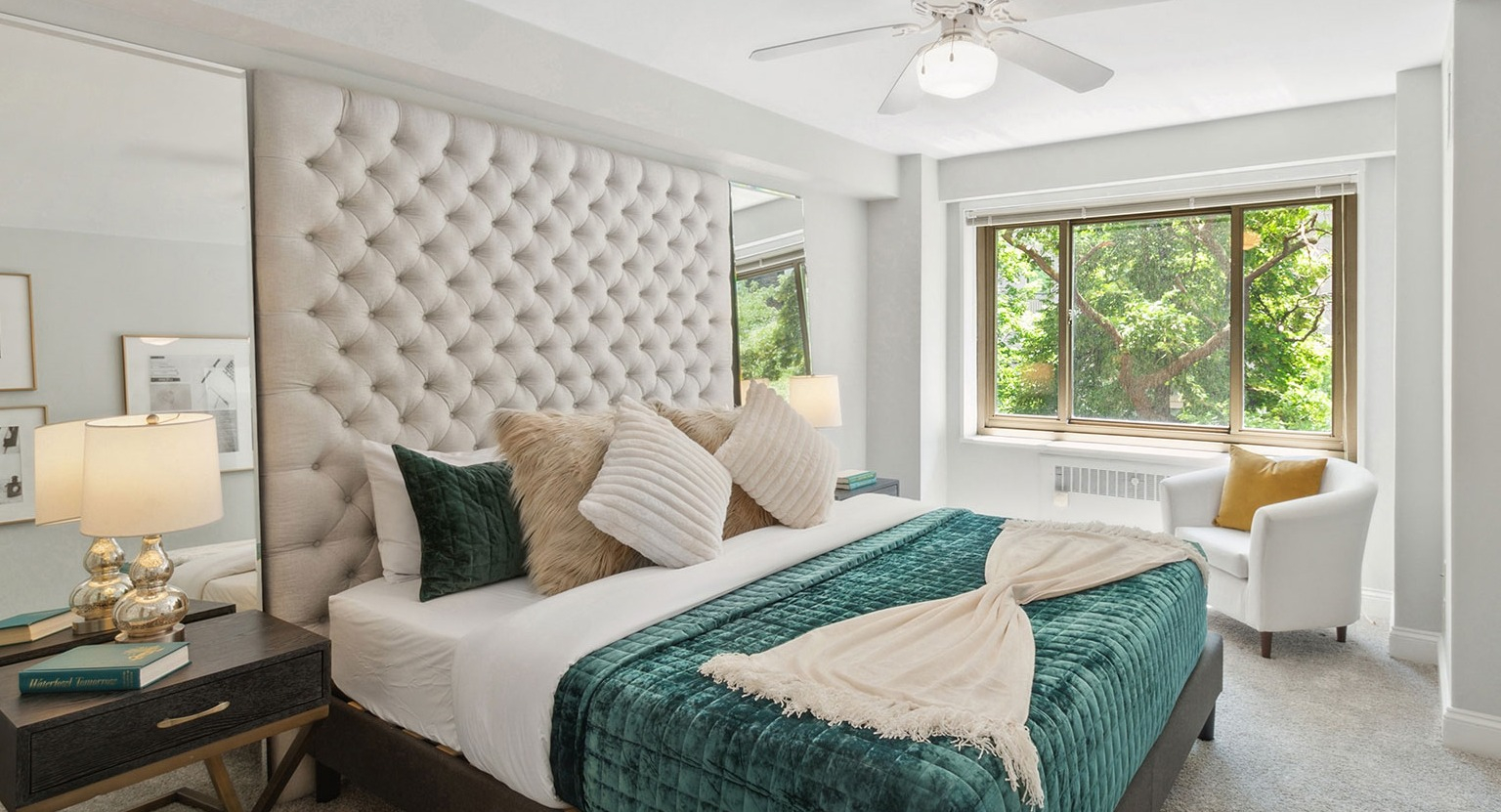 Serene bedroom with tufted headboard, ceiling fan, large window, and plush bedding at 1350–1360 Lake Shore Drive apartments in Chicago