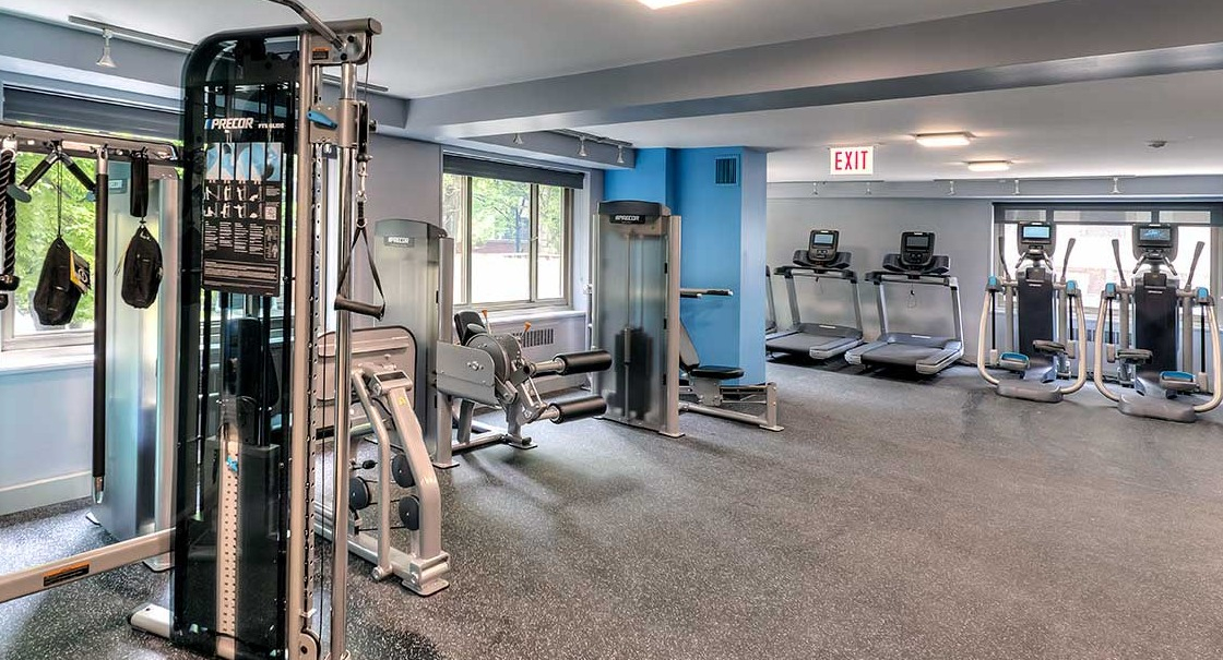 Modern fitness center featuring Precor strength machines and treadmills with window views at 1350-1360 Lake Shore Drive apartments in Chicago