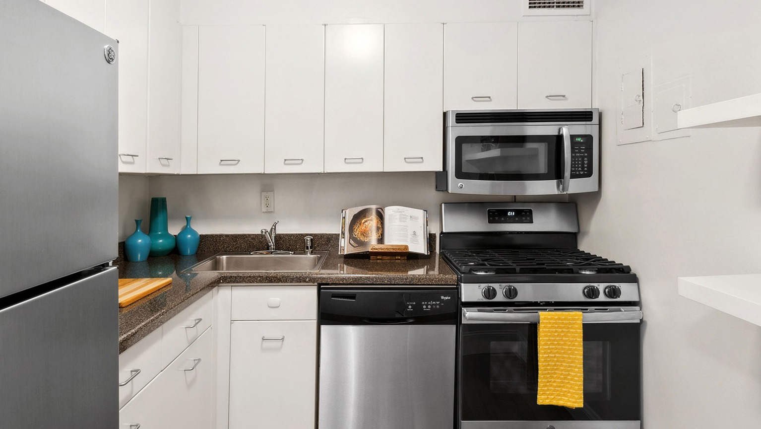Modern galley kitchen with white cabinets, stone-look counters, stainless fridge, gas range, microwave, and dishwasher at 1350–1360 Lake Shore Drive in Chicago