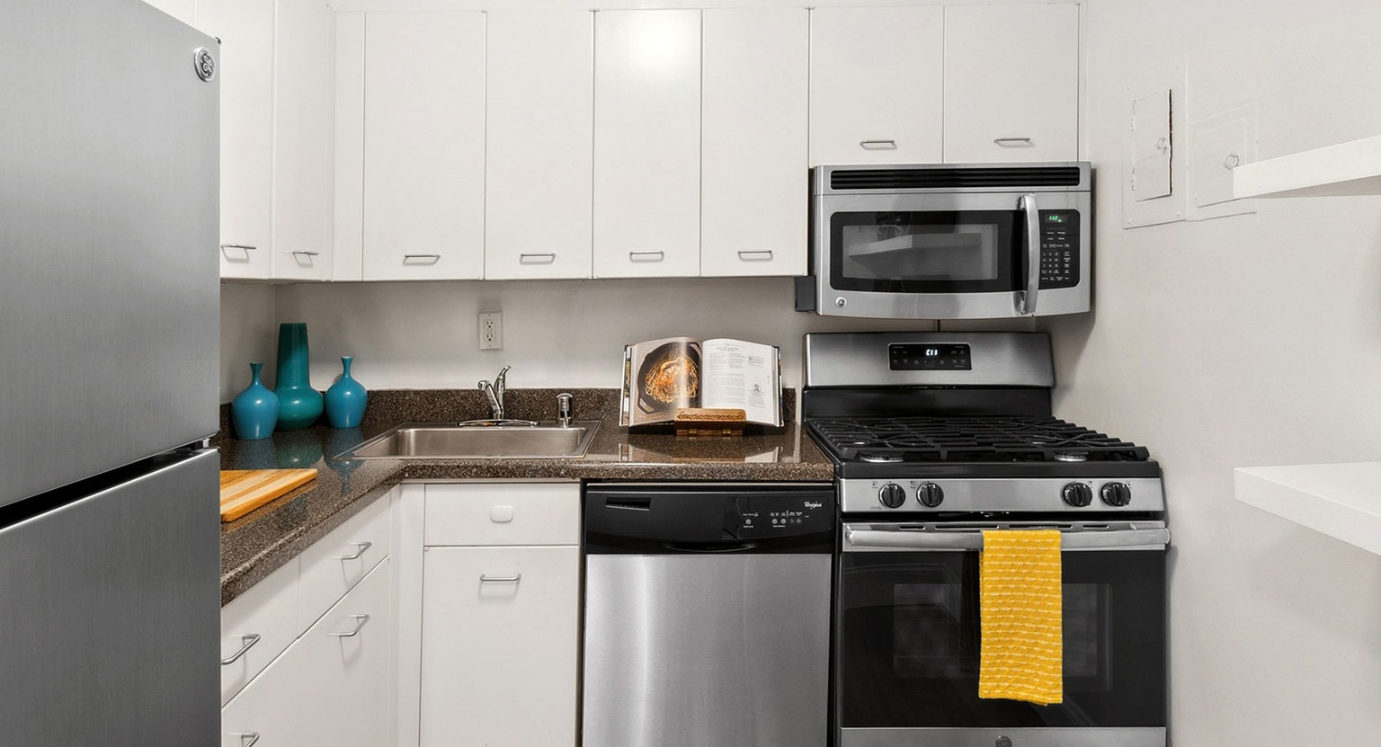 Modern galley kitchen with white cabinets, stone-look counters, stainless fridge, gas range, microwave, and dishwasher at 1350–1360 Lake Shore Drive in Chicago