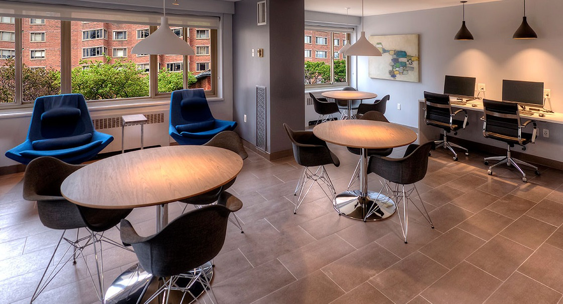 Resident lounge and business center with café tables, lounge chairs, desktop computers, and printer at 1350–1360 Lake Shore Drive apartments in Chicago
