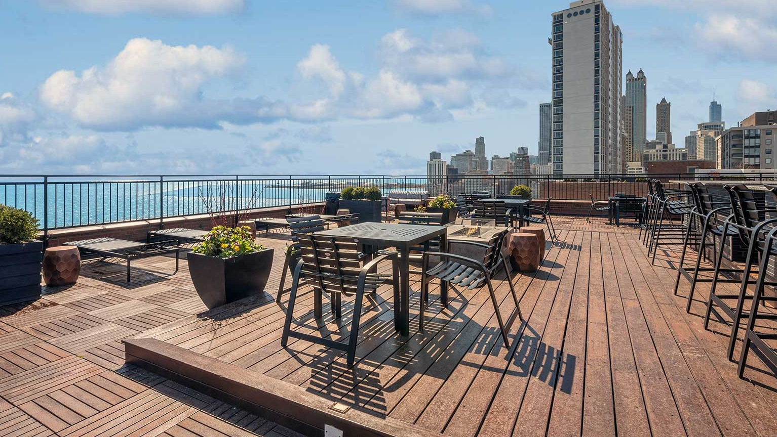 Rooftop dining area with tables, bar seating, planters, and broad Chicago skyline and lake views at 1350–1360 Lake Shore Drive apartments