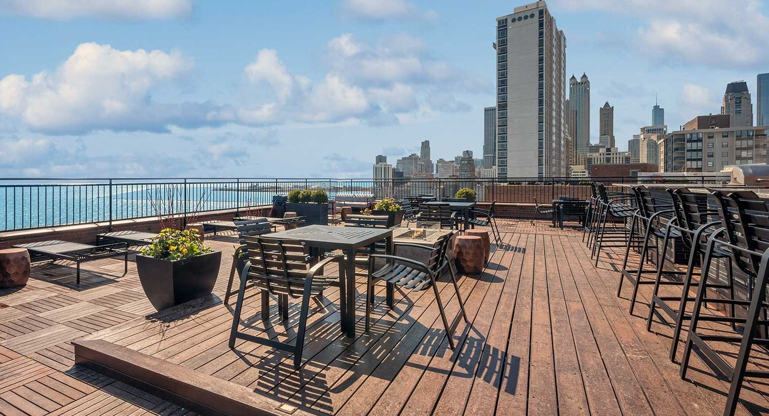 Rooftop dining area with tables, bar seating, planters, and broad Chicago skyline and lake views at 1350–1360 Lake Shore Drive apartments