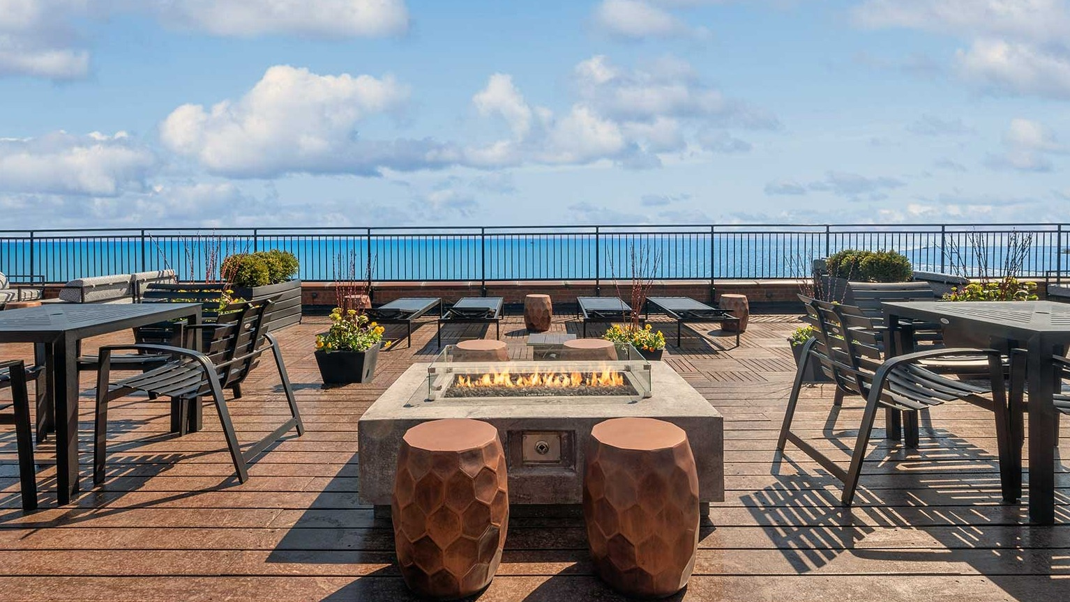 Rooftop fire pit lounge with dining tables and uninterrupted Lake Michigan views at 1350–1360 Lake Shore Drive apartments in Chicago