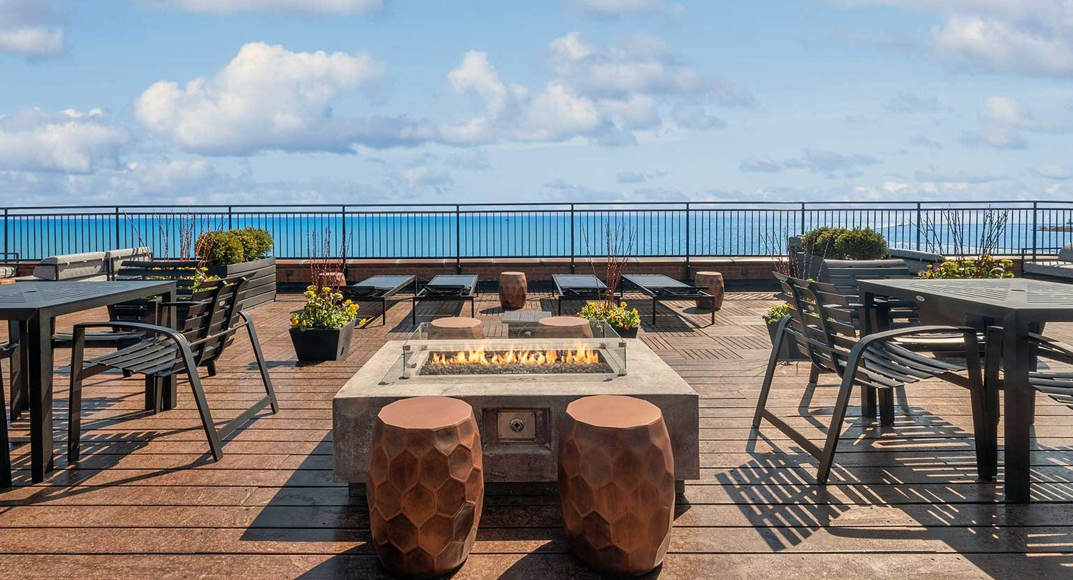 Rooftop fire pit lounge with dining tables and uninterrupted Lake Michigan views at 1350–1360 Lake Shore Drive apartments in Chicago