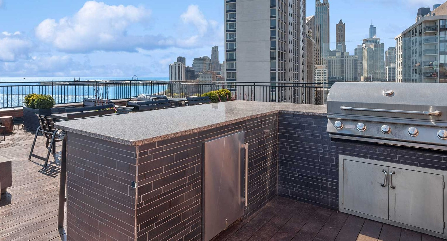 Rooftop grilling station with built-in gas grill, counter space, fire pit seating, and sweeping lake and skyline views at 1350–1360 Lake Shore Drive in Chicago