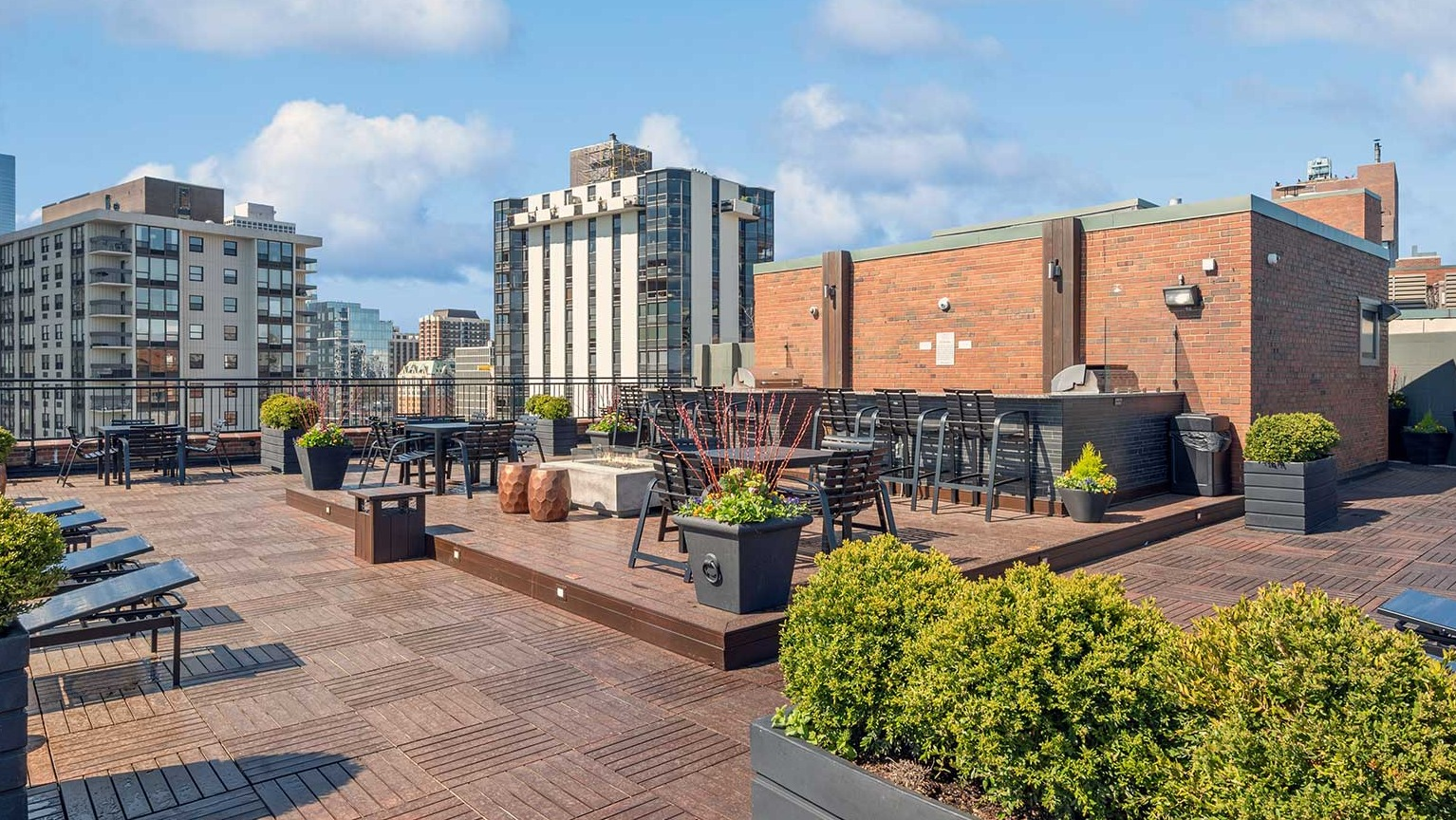 Multi-level rooftop terrace with planters, dining tables, chaise loungers, and social seating at 1350–1360 Lake Shore Drive apartments in Chicago