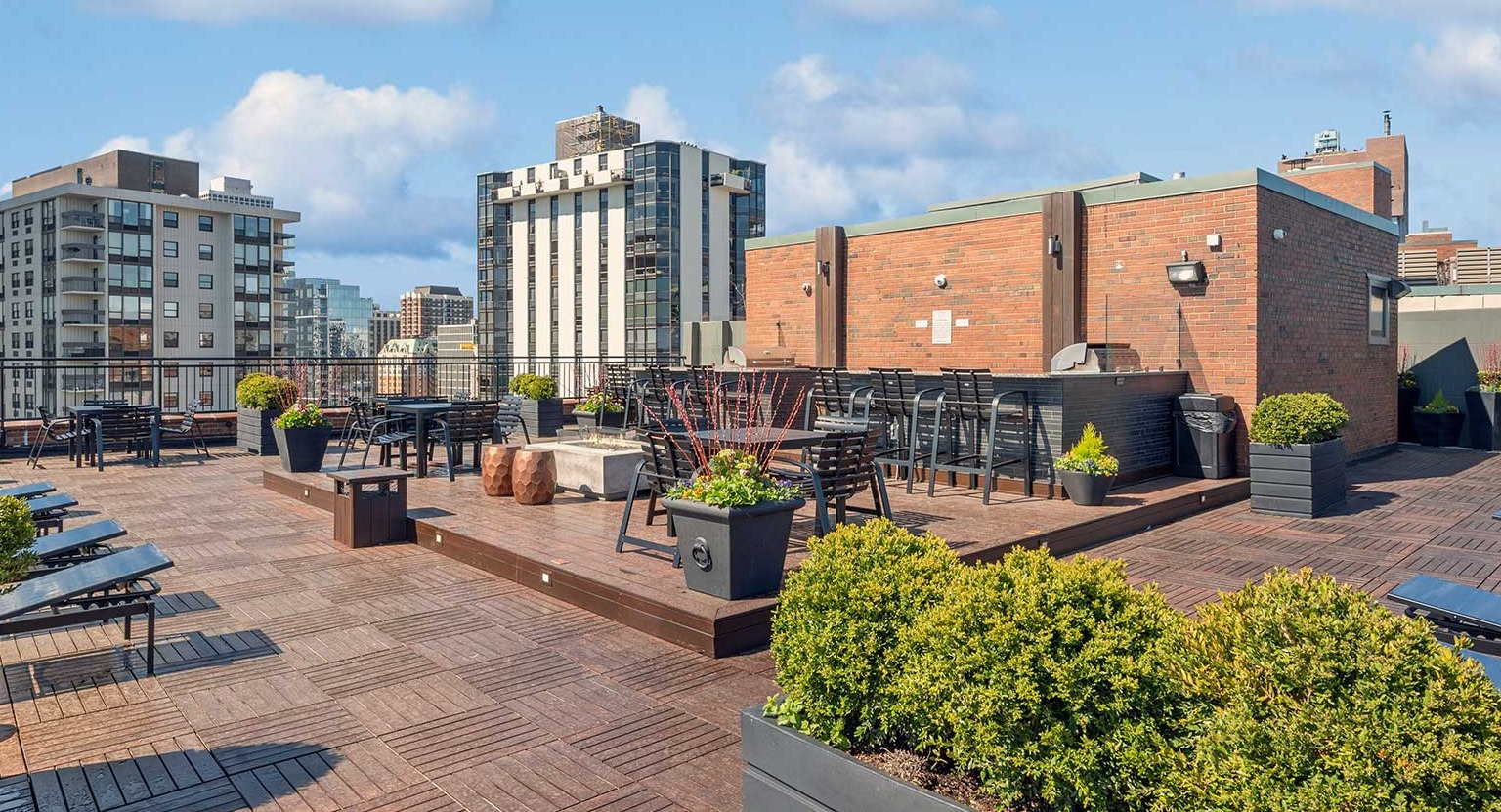 Multi-level rooftop terrace with planters, dining tables, chaise loungers, and social seating at 1350–1360 Lake Shore Drive apartments in Chicago