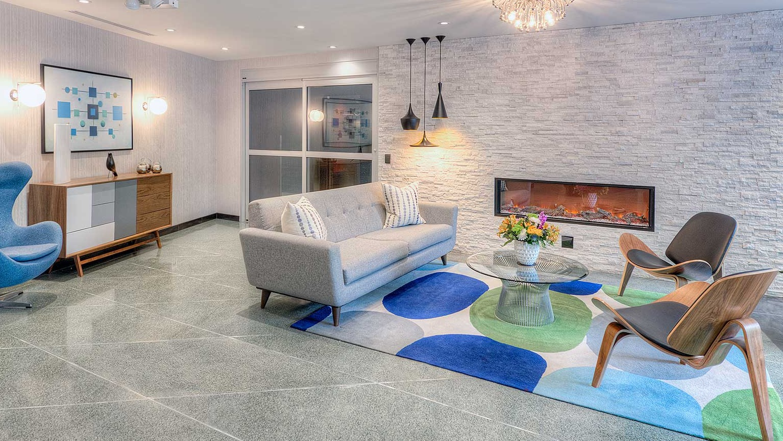 Cozy lounge at 1350 Lake Shore Drive featuring modern sofa, sculptural chairs, fireplace, and a vibrant area rug in Chicago