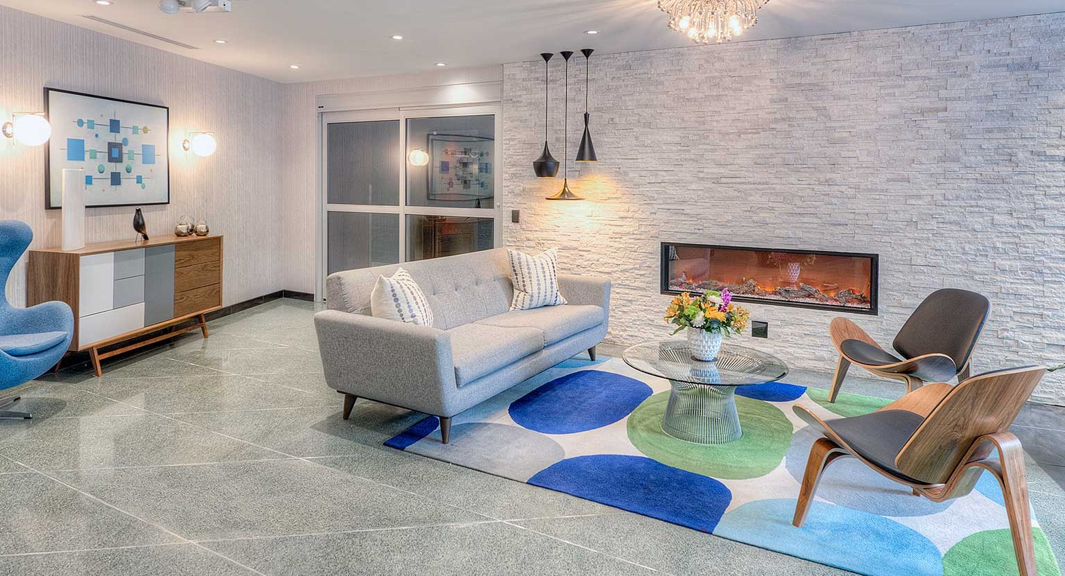 Cozy lounge at 1350 Lake Shore Drive featuring modern sofa, sculptural chairs, fireplace, and a vibrant area rug in Chicago