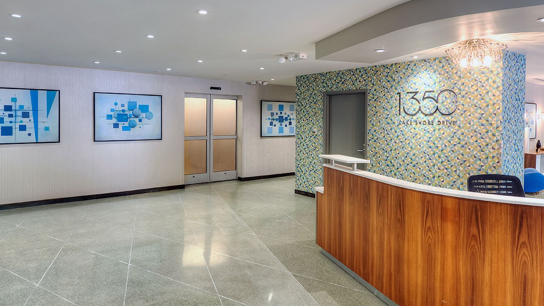 Contemporary 1350 Lake Shore Drive lobby with curved wood reception desk, geometric tile accent wall, and building logo in Chicago