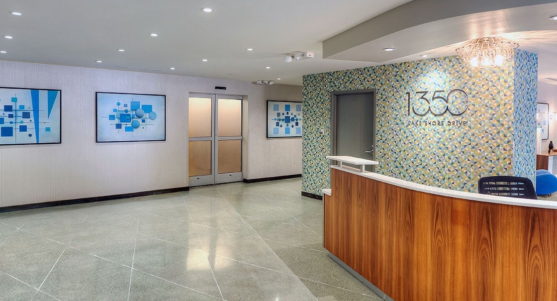 Contemporary 1350 Lake Shore Drive lobby with curved wood reception desk, geometric tile accent wall, and building logo in Chicago