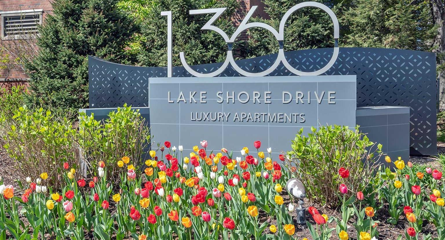 Entrance monument sign for 1360 Lake Shore Drive luxury apartments, surrounded by colorful tulips and landscaped grounds in Chicago