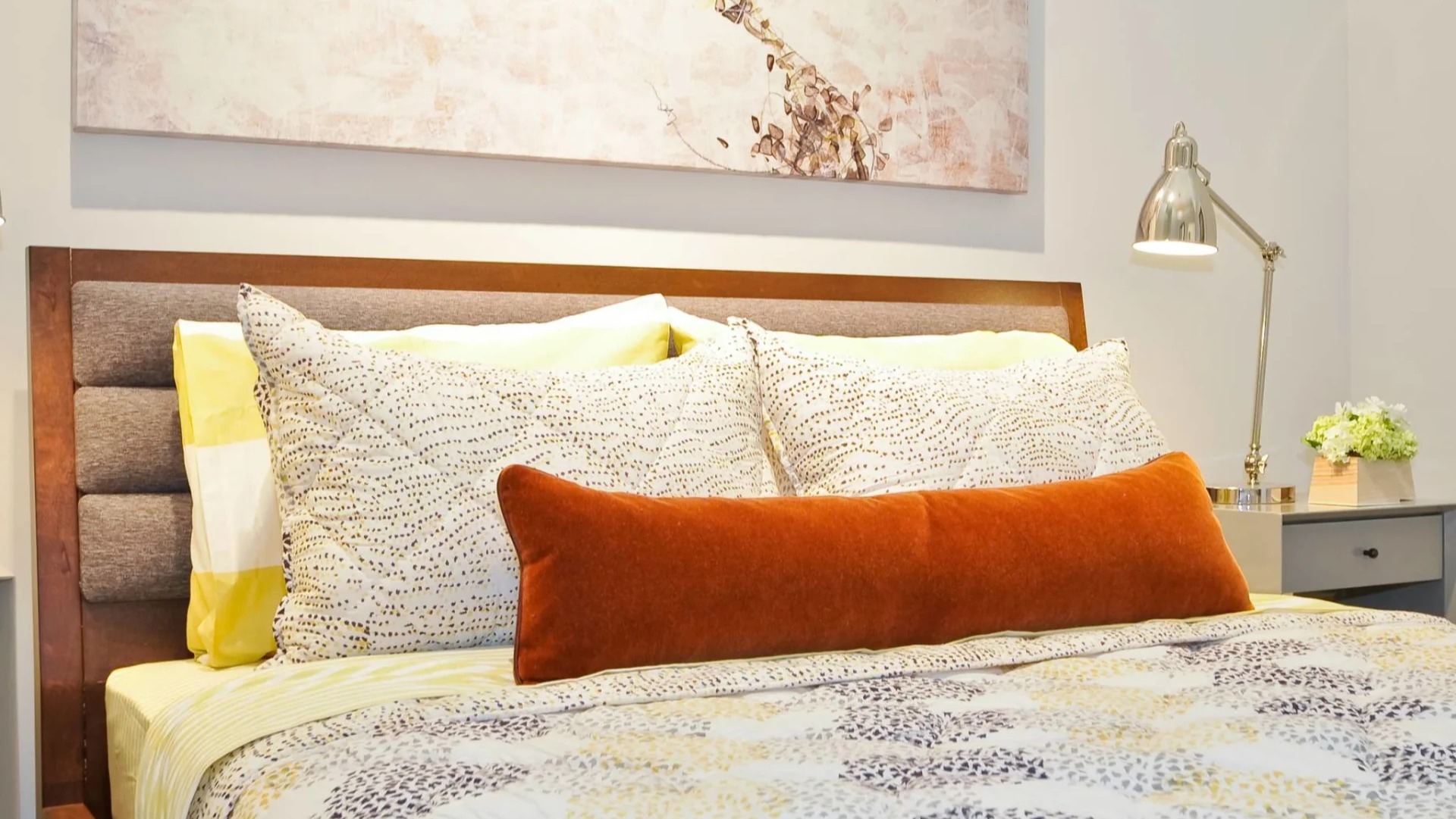 Cozy bedroom at 13thirteen Randolph Street Lofts with upholstered headboard, layered bedding, bedside lamps, and calming artwork for Chicago renters