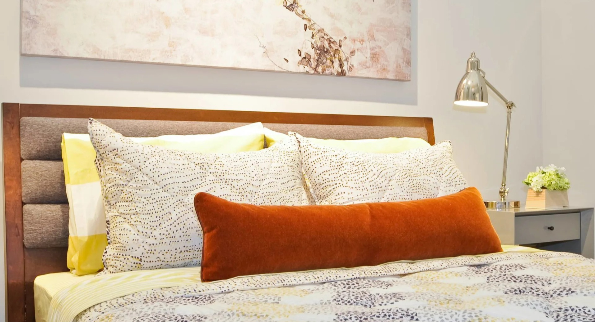 Cozy bedroom at 13thirteen Randolph Street Lofts with upholstered headboard, layered bedding, bedside lamps, and calming artwork for Chicago renters