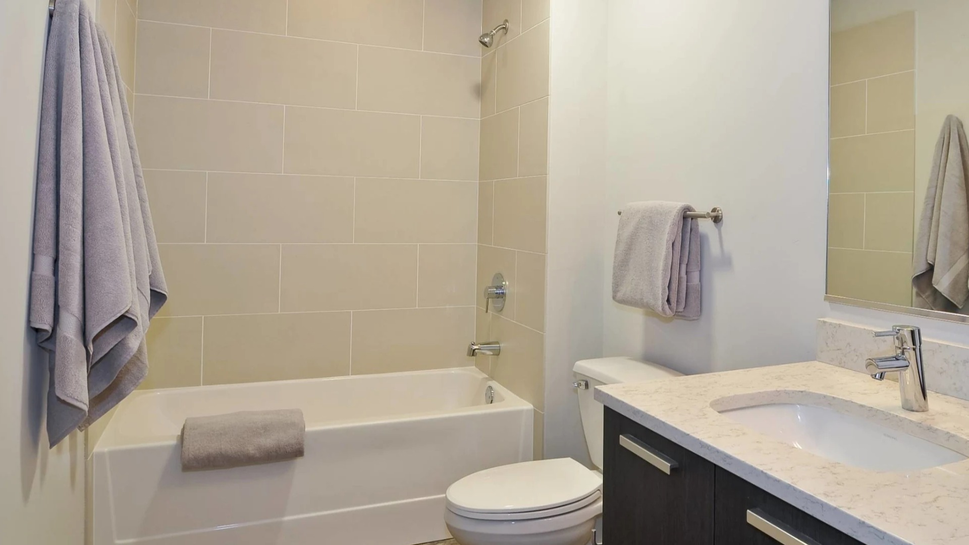 Modern bathroom at 13thirteen Randolph Street Lofts with large tiled tub-shower, quartz vanity, and soft lighting for a clean, relaxing feel in Chicago