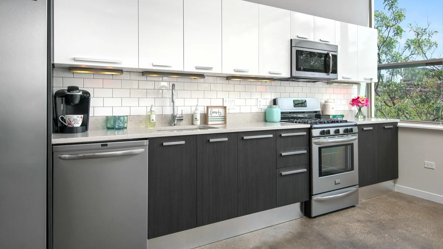 Modern kitchen at 13thirteen Randolph Street Lofts with white subway tile, two-tone cabinets, stainless appliances, and bright window light for Chicago renters