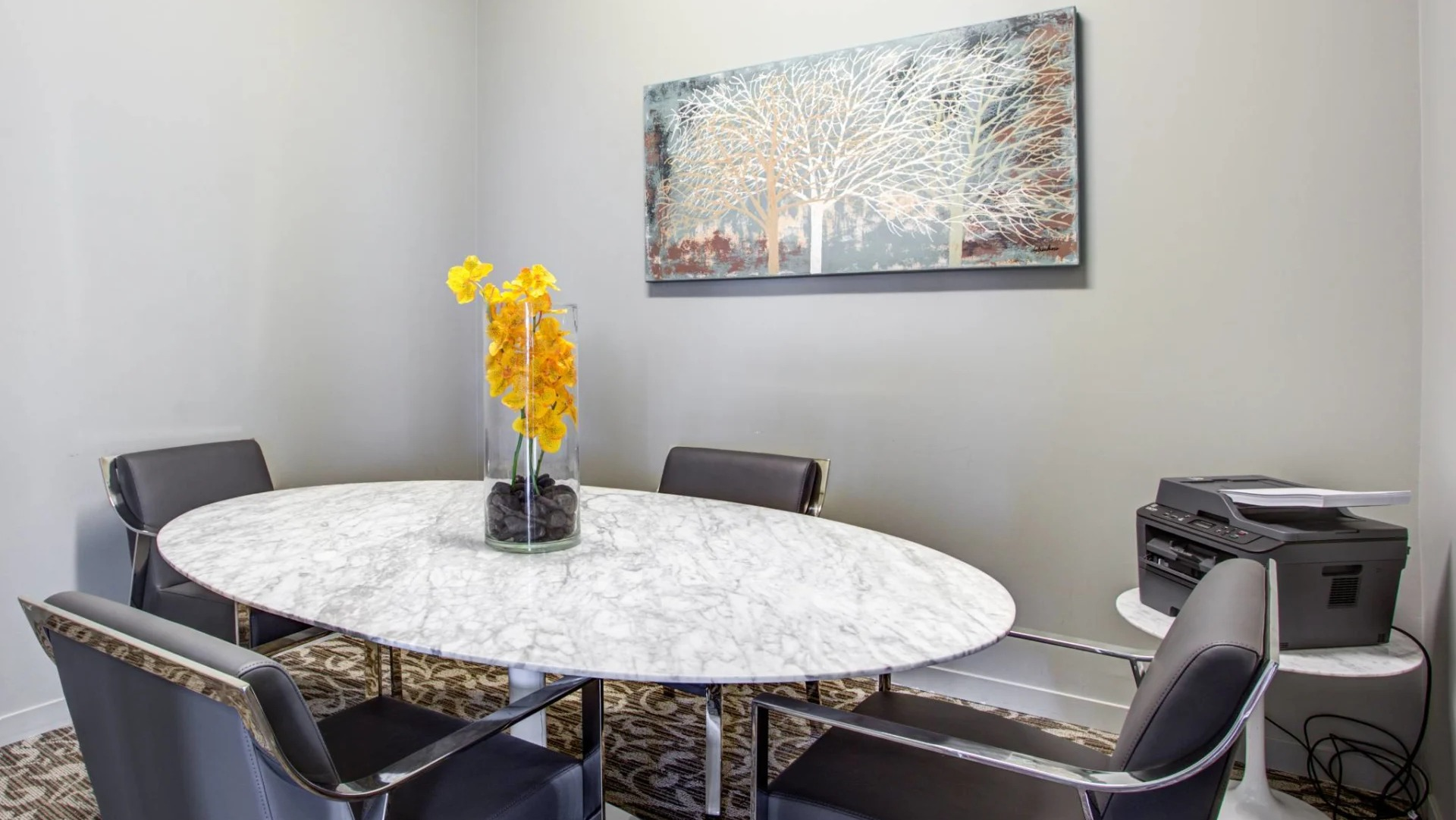 Private conference room at 13thirteen Randolph Street Lofts with round marble table, four leather chairs, and printer—ideal for remote work in Chicago