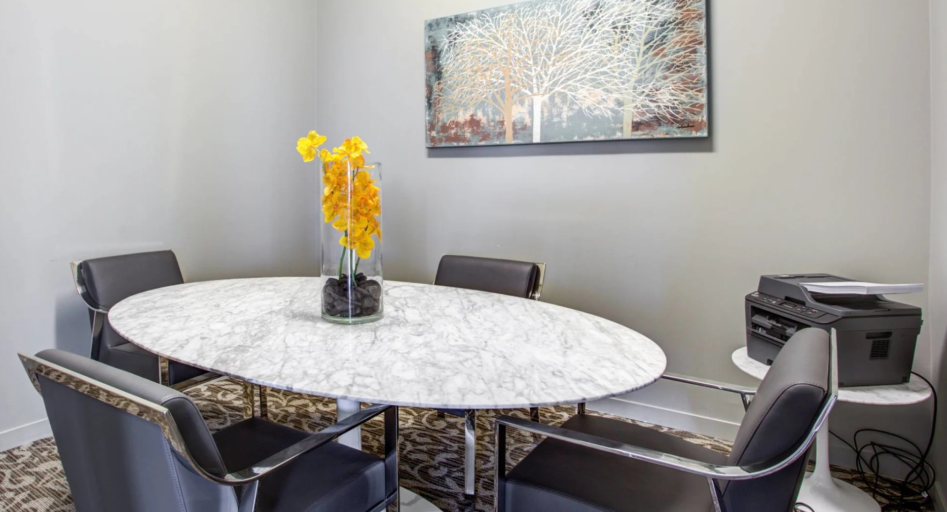 Private conference room at 13thirteen Randolph Street Lofts with round marble table, four leather chairs, and printer—ideal for remote work in Chicago