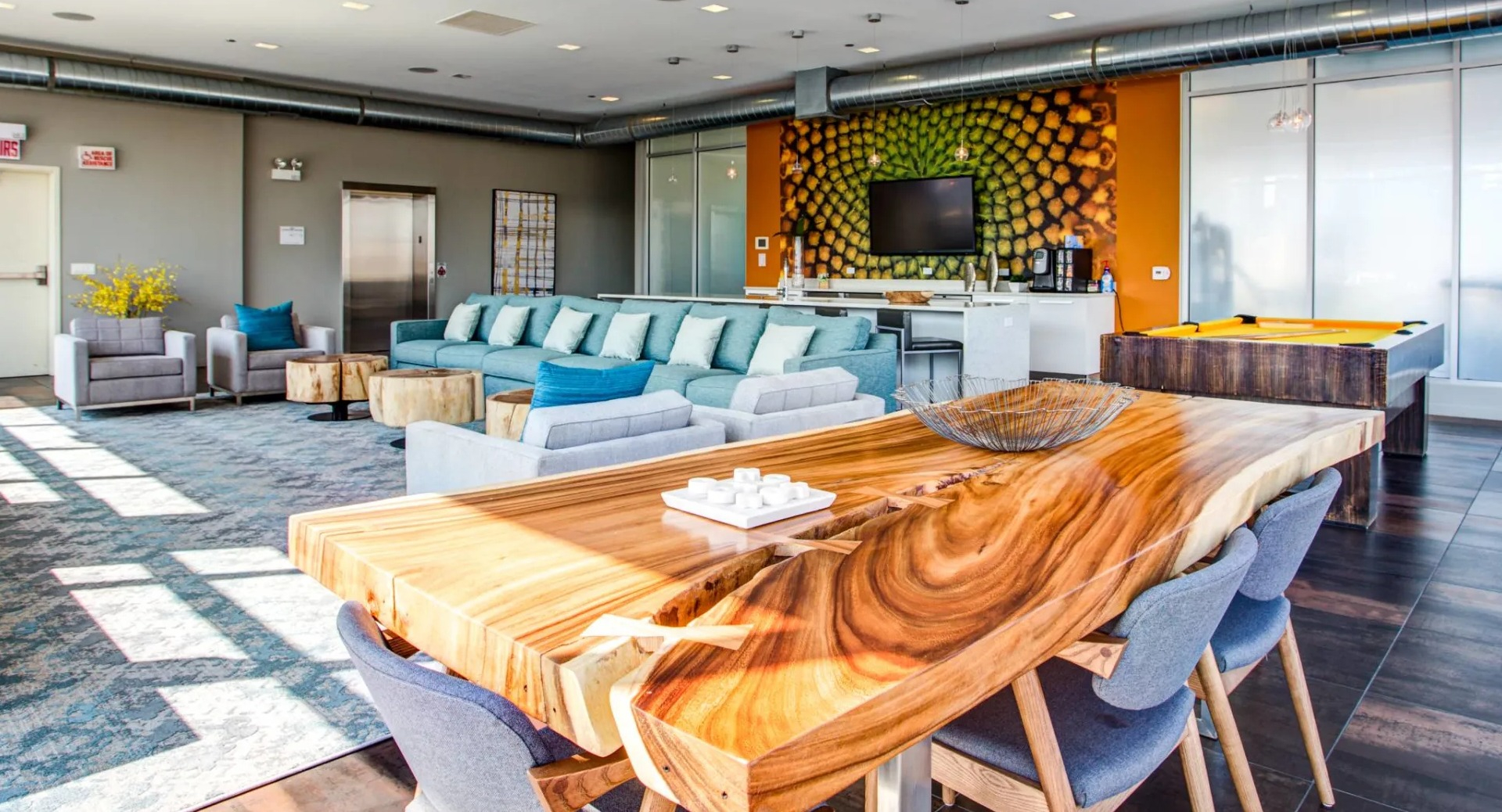 Expansive resident clubroom at 13thirteen Randolph Street Lofts with lounge seating, live-edge table, TV, and pool table—ideal for hosting in Chicago