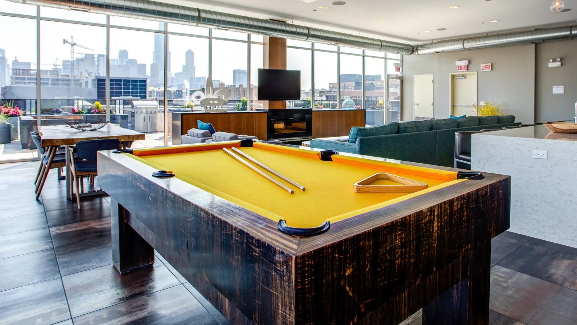 Spacious resident clubroom at 13thirteen Randolph Street Lofts featuring a pool table, TV lounge, chef’s island kitchen, and floor-to-ceiling windows