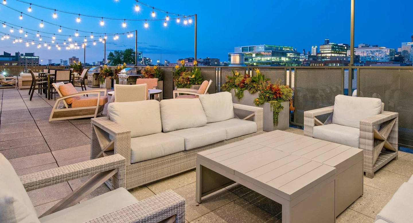 Rooftop lounge at 13thirteen Randolph Street Lofts with cushioned seating, string lights, and sweeping nighttime Chicago skyline views