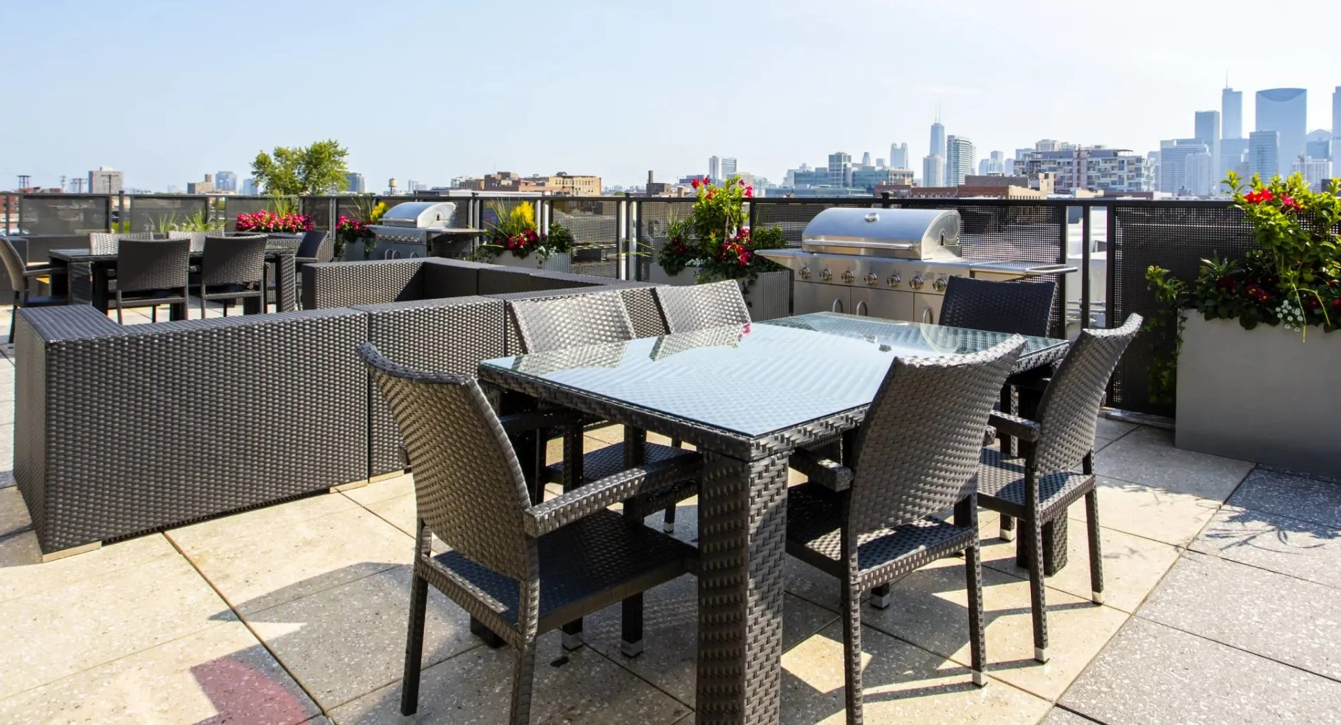 Rooftop terrace at 13thirteen Randolph Street Lofts offering dining tables, grills, wicker seating, planters, and sunny Chicago skyline views